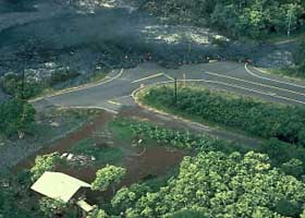 Four-way intersection in Kalapana Gardens, with two legs of intersection covered in lava