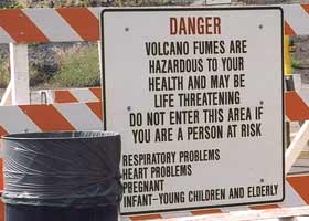 Entry sign on barricade, next to trash can: 'Danger | Volcano fumes are | dangerous to your | health and may be | life threatening | Do not enter this area if | you are a person at risk | Respiratory problems | Heart problems | Pregnant | Infant-young children and elderly'