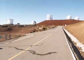 Junction with side road, with five telescopes atop summit in the background