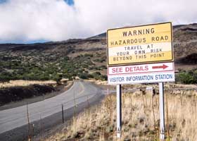 Sign: 'Warning Hazardous Road | Travel At Your Own Risk Beyond This Point'; 'See Details' at Visitor Information Station