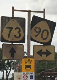 Yellow TheBus stop marker, topped with old route 73 and 90 markers