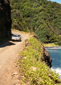 Narrow, barely paved cliffside road high above the ocean, with pebbles in road and no guardrails